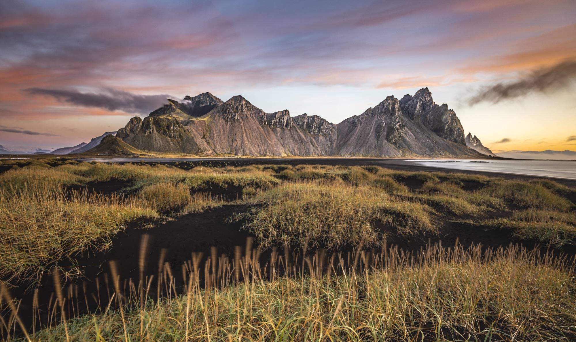 Vestrahorn mountain beyond grass-covered black sand dunes